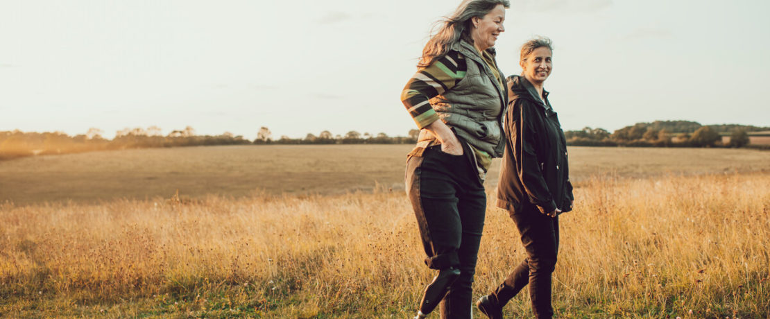 Two women walking in a field on a summer evening
